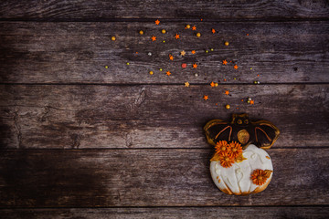 Hand painted gingerbread cookie scary Halloween old jack-o-lantern pumpkin with colored sprinkles on wooden background. Top view