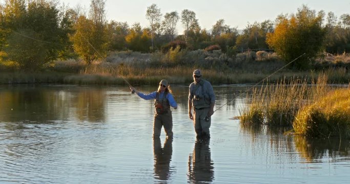 Caucasian couple fly fishing in river