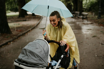 Mother enjoying outdoors in park with her baby while it's raining.