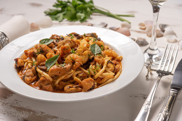 Pasta with sea fruit in white plate on a white wooden background, soft light. Spaghetti ai frutti di mare, seafood mediterranean gastronomy