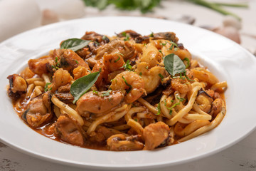 Pasta with sea fruit in white plate on a white wooden background, soft light. Spaghetti ai frutti di mare, seafood mediterranean gastronomy