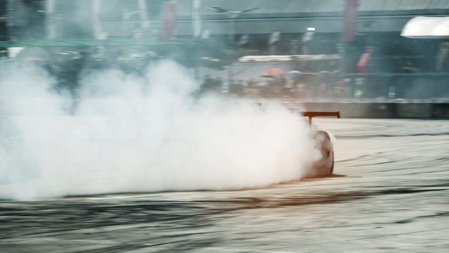 A lot of smoke is caused by a professional drift driver driving on a racetrack.