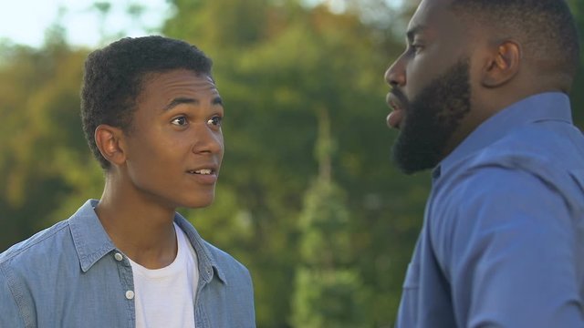 Afro-american teenager arguing with father having own opinion, rebellious age