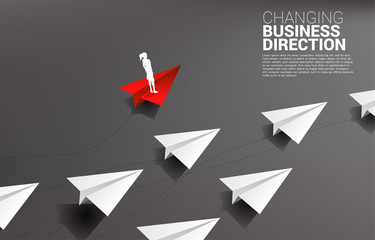 Silhouette of businesswoman standing on red origami paper airplane is move apart direction from group of white. Business Concept of disruption and niche marketing