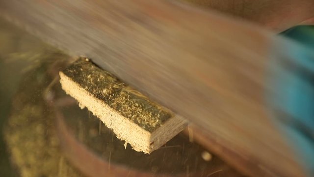 A carpenter saws an old board with a hand saw in the open air, close-up