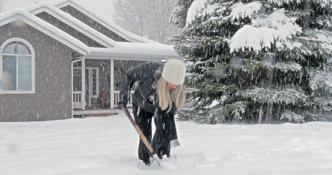 Caucasian woman shoveling snow in front yard