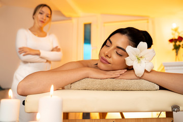 Obraz na płótnie Canvas Pretty girl with flower in her hair enjoying relaxed in massage salon 