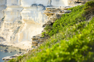 (Selective focus) Stunning view of a rock formations illuminated during sunset in the foreground and a blurred limestone cliff in the background.