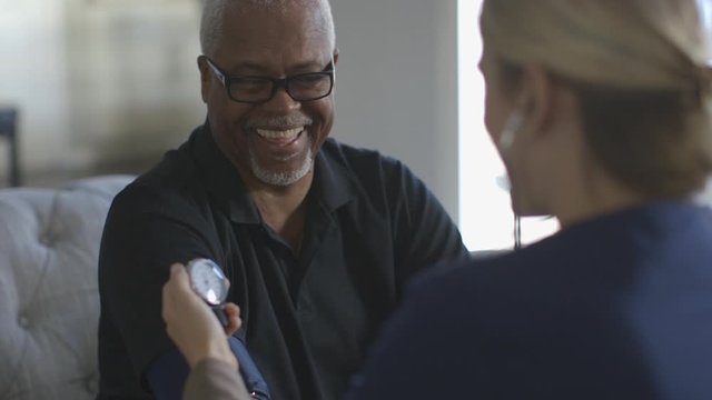 Caregiver checking blood pressure of patient in home