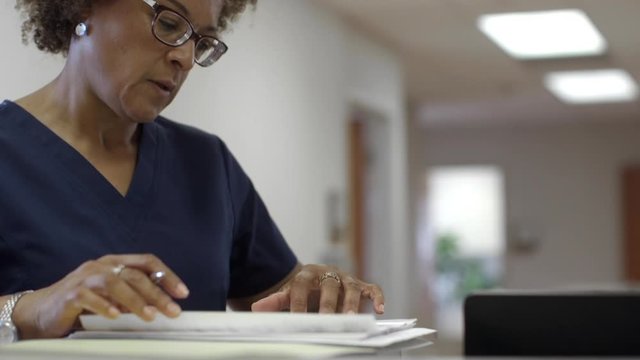 Black Doctor Writing On Paperwork In Hospital