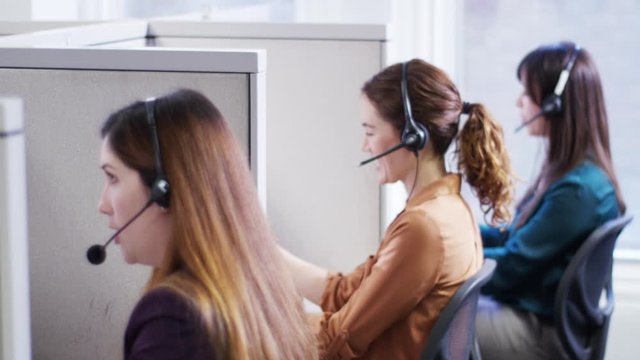 Businesswomen talking on headsets in call center cubicles