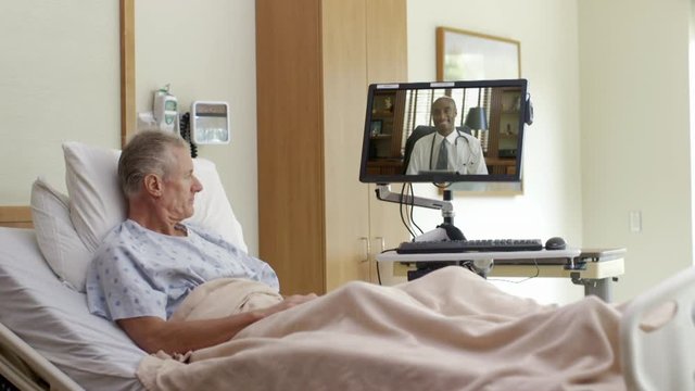 Patient in hospital bed video chatting with doctor on computer