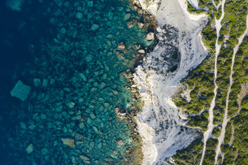 View from above, stunning aerial view of a white limestone cliff and rock formations bathed by a turquoise clear water, Bonifacio, South of Corsica, France.