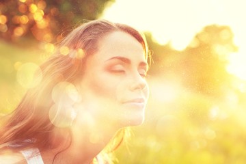 Fototapeta premium Young woman on field under sunset light