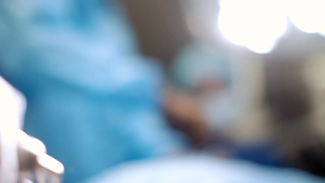 Nurse handing forceps to surgeon in operating room