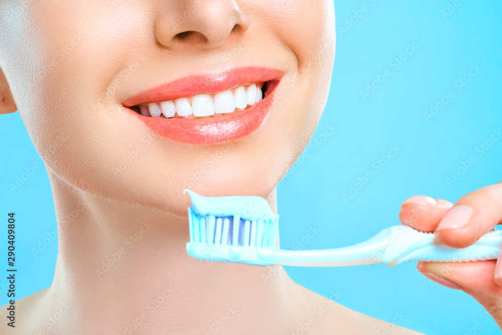 Wall mural portrait of attractive caucasian smiling woman isolated on white studio shot brushing her teeth