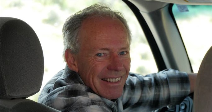 Older Caucasian man smiling in car