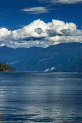 Fototapeta na wymiar Thick clouds roll over the giant mountains near Earl's Cove, BC