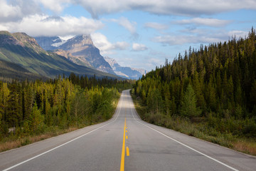 Scenic road in the Canadian Rockies during a vibrant sunny and cloudy summer morning. Taken in Icefields Parkway, Banff National Park, Alberta, Canada.