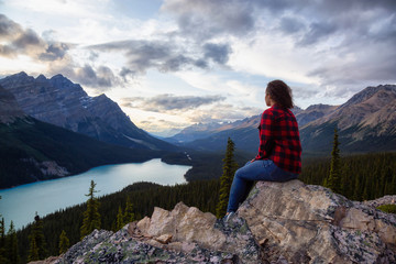 Adventurous girl on the edge of a cliff overlooking the beautiful Canadian Rockies and Peyto Lake...