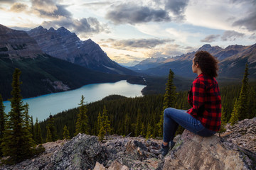 Adventurous girl on the edge of a cliff overlooking the beautiful Canadian Rockies and Peyto Lake...