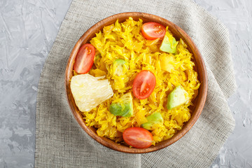 Fried pomelo with tomatoes and avocado in wooden plate on gray concrete background. Top view.