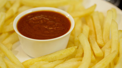 French fries on a plate with a ketchup bowl in the center Macro