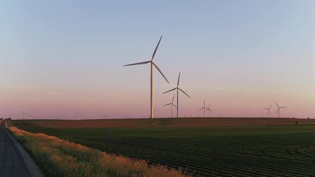 Driving on road near wind farm at sunset