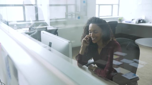 Mixed race businesswoman talking on cell phone in startup office