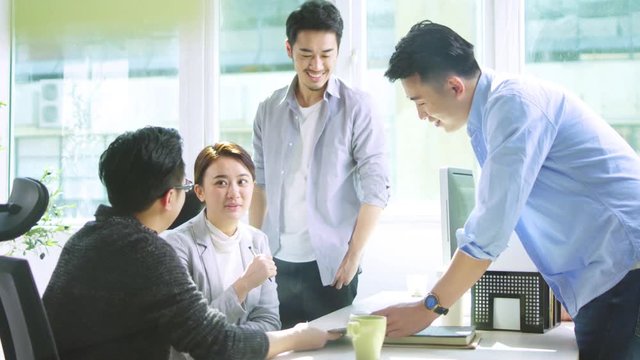 four young asian people discussing business using tablet PC in office