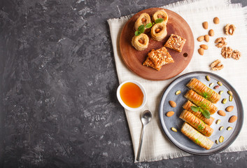 Set of various traditional arabic sweets: baklava, kunafa, basbus in  ceramic plates on a black concrete background. top view.