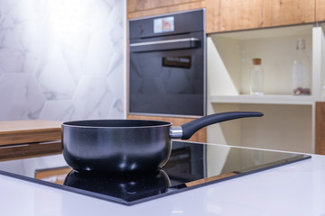 Frying pan on modern black induction stove, cooker, hob or built in cooktop with ceramic top in...