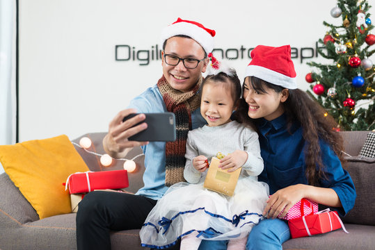 Asian family father mother daughter selfie with smartphones, Christmas.