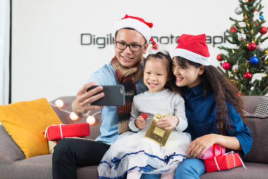 Asian family father mother daughter selfie with smartphones, Christmas.