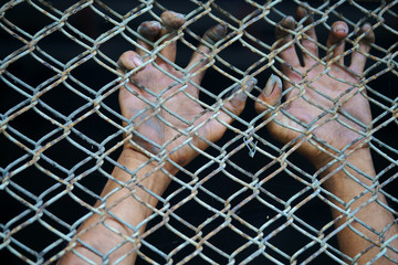 close up of dirty hands in jail background.