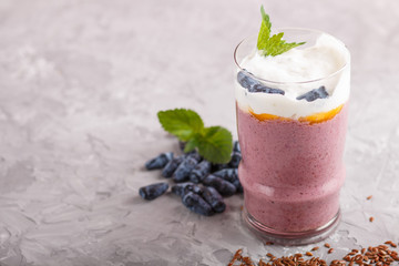 smoothie with honeysuckle, linen and chia in a glass on gray concrete background. side view.