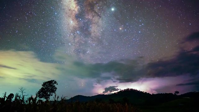 Time lapse day to night see the Milky way with lightning and clouds rolling in the sky.
