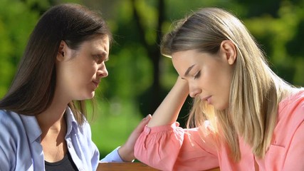 Best friend supporting and comforting sad crying female in park, trust and care