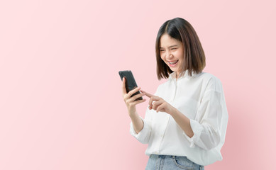 Naklejka premium Young smiling Asian woman holding smartphone isolated on light pink background.