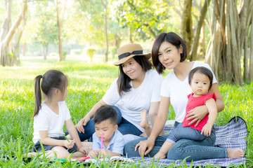 Beautiful young asian parent family portrait picnic in the park, kid or children and mother love happy and cheerful together in summer at garden, lifestyle concept.