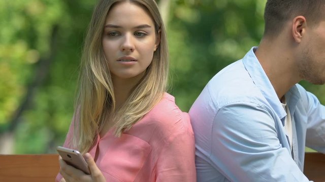 Jealous woman with phone watching boyfriend chatting on cellphone, mistrust