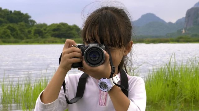 Children little cute asian girl 7 years old smile and enjoying making photo traveling in nature Mountains and rivers in evening.  Adventure holidays