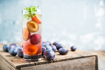 Cocktail with plums and thyme on the rustic background. Selective focus. Shallow depth of field.