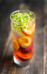 Cocktail with plums and thyme on the rustic background. Selective focus. Shallow depth of field.