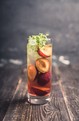 Cocktail with plums and thyme on the rustic background. Selective focus. Shallow depth of field.