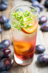 Cocktail with plums and thyme on the rustic background. Selective focus. Shallow depth of field.