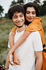 Close up of a loving couple having fun while dating outdoor. Beautiful young couple while man is piggybacking her girlfriend.