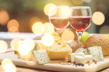 Assortment of cheese on board and two glasses of wine