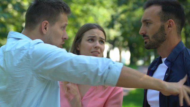 Two men arguing and pushing each other for attention of woman, confrontation