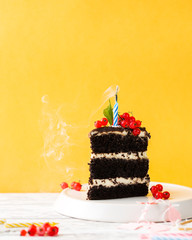 Chocolate piece of cake with candle on a bright yellow background